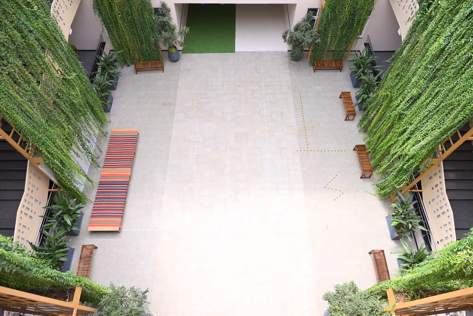 Central indoor courtyard with hanging vines, planters, and wooden benches