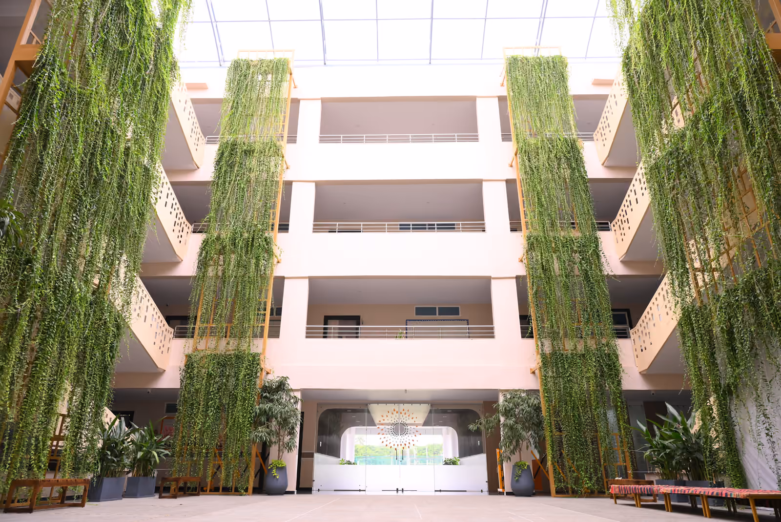 Four-story school atrium with floor-to-ceiling vertical gardens under a glass skylight