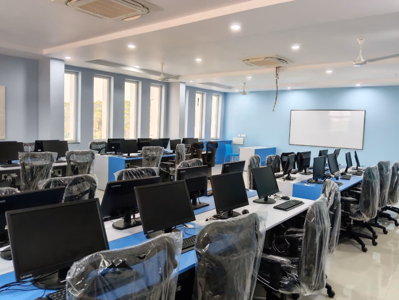 Computer lab with rows of desktop workstations, keyboards, and ergonomic chairs