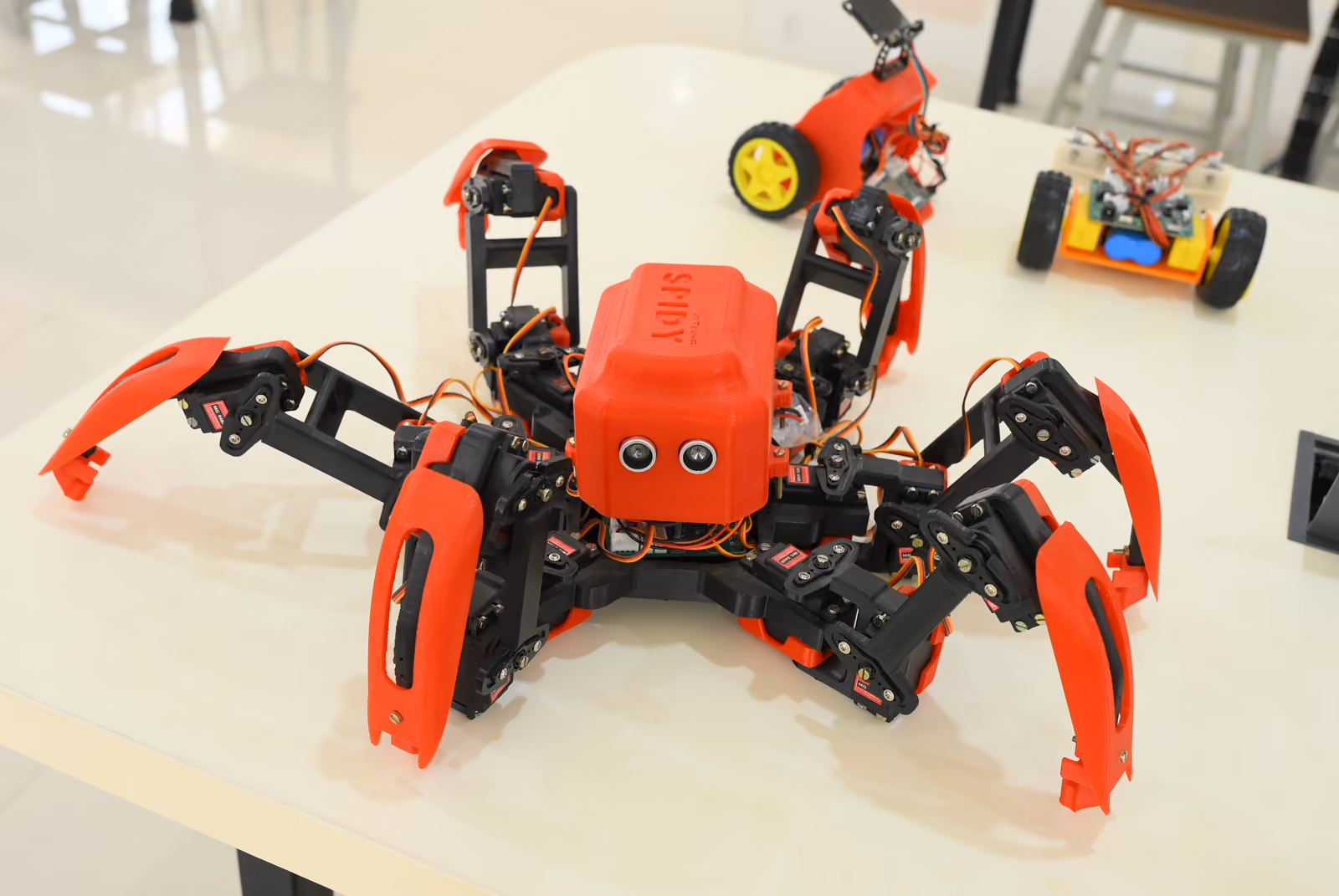 Red hexapod robot named SPIDY with ultrasonic sensors in the robotics lab