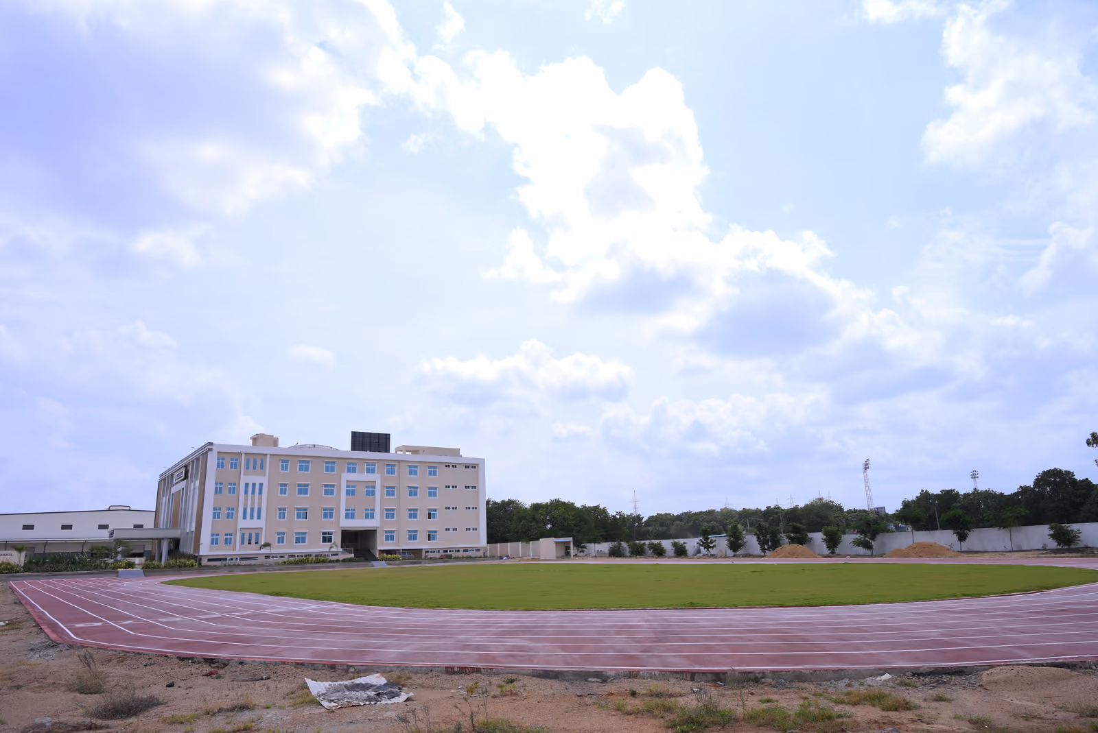 Red running track and green sports field in front of the school building